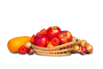 Ripe red apples in wicker basket and group of vegetables