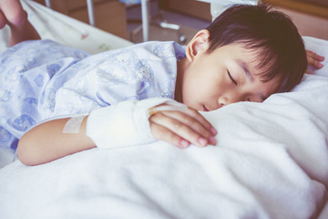 Obraz na płótnie Canvas Asian boy sleeping on sickbed, saline intravenous (IV) on hand.