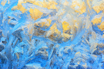 Window glass covered with ice pattern against sunset