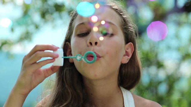 Attractive girl blowing soap bubbles. Female with soap bubbles