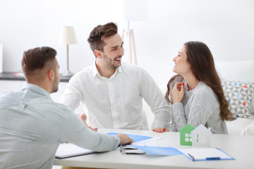 Happy family with estate agent,  in bright office