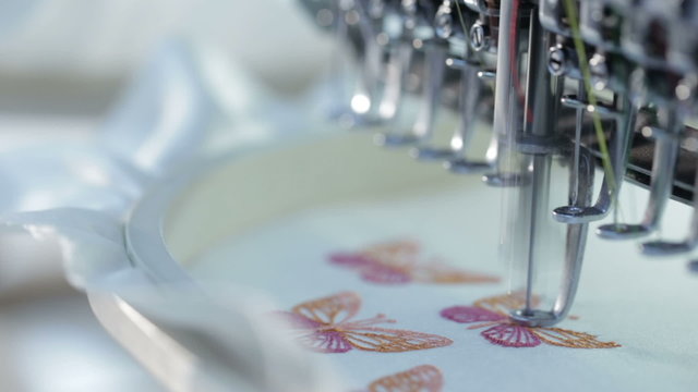 Automatic sewing machine embroider the butterfly colorful pattern on white fabric. Industrial textiles