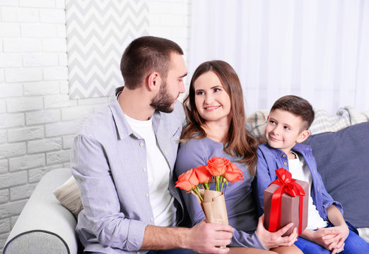 Husband and son giving gift box and roses to wife