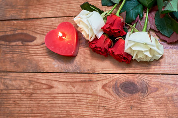 bunch of red roses with red candle on wooden background