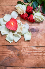 bunch of red roses with red candle on wooden background