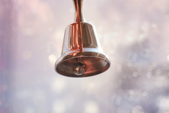 A small bell in the girl's hand on a neutral background, close-up