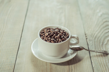 white cup with coffe grain on white wooden table
