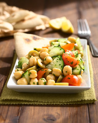Chickpea salad with green olives, cucumber, cherry tomato and parsley, photographed with natural light (Selective Focus, Focus one third into the salad)