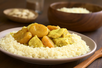 Chicken and dried apricot stew, seasoned with turmeric, cinnamon and honey, served on couscous on plate, photographed with natural light (Selective Focus, Focus in the middle of the dish)