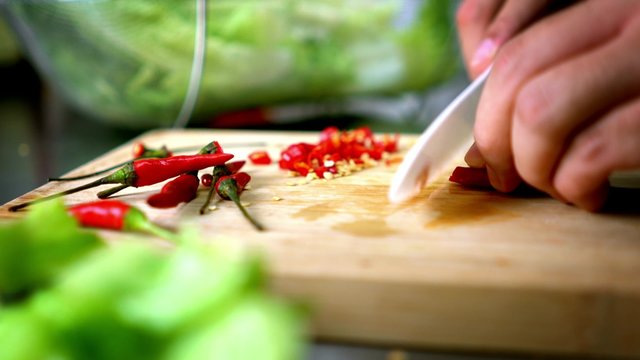 Man Cutting Chili Lettuce on Cutting Board with Ceramic White Knife - Close Up 4K Resolution