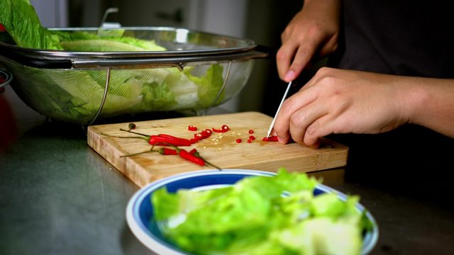 Man Slices Chili Lettuce on Cutting Board with White Knife - 4K Resolution