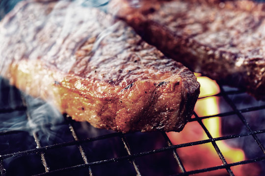 Two pieces of striploin steak on grill, toned