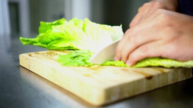 Man Cutting Lettuce on Board Cutting with Ceramic White Knife - Close Up 4K Resolution