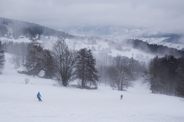 clouds over snowy ski slope with skiers