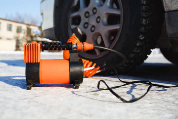Car air compressor in working position at snow. Self-inflating wheels, automobile tire pressure...