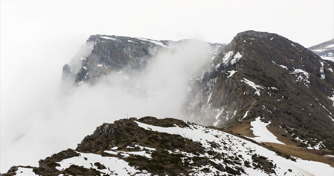High rocky mountain peak covered with snow and fog moving. 4k timelapse.