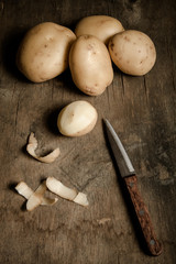 Potatoes with peelings on old wooden background. Toned