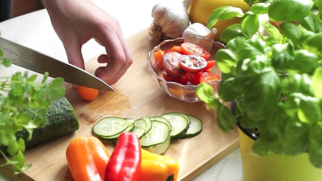 Young woman cutting vegetables for salad