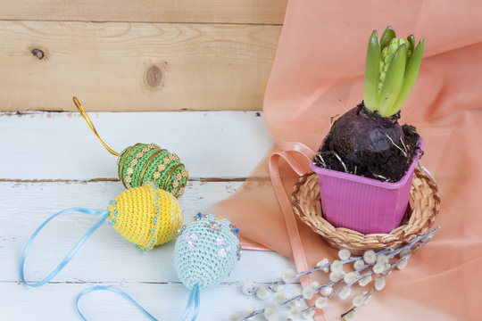 Hyacinth in pot and handmade Happy Easter eggs on a light wooden background