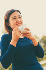 Smile asian woman holding cup of coffee with nature background.