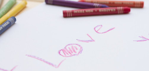 Разноцветные пастельные мелки (карандаши) и надпись на белом листе бумаги на английском 