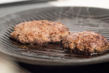 Fresh meat cutlets in a frying pan grill