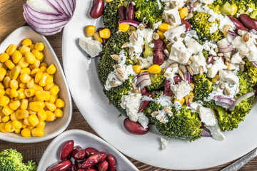 Vegetarian salad with broccoli, beans, corn, onion and feta cheese.