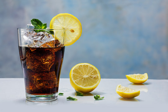 glass of cola or coke with ice cubes, lemon slice and peppermint