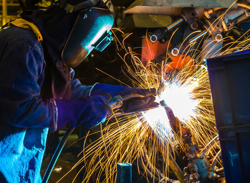 Employee welding Industrial automotive part in factory