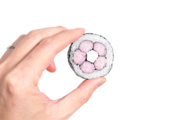 Hand holding a piece a maki roll against white background