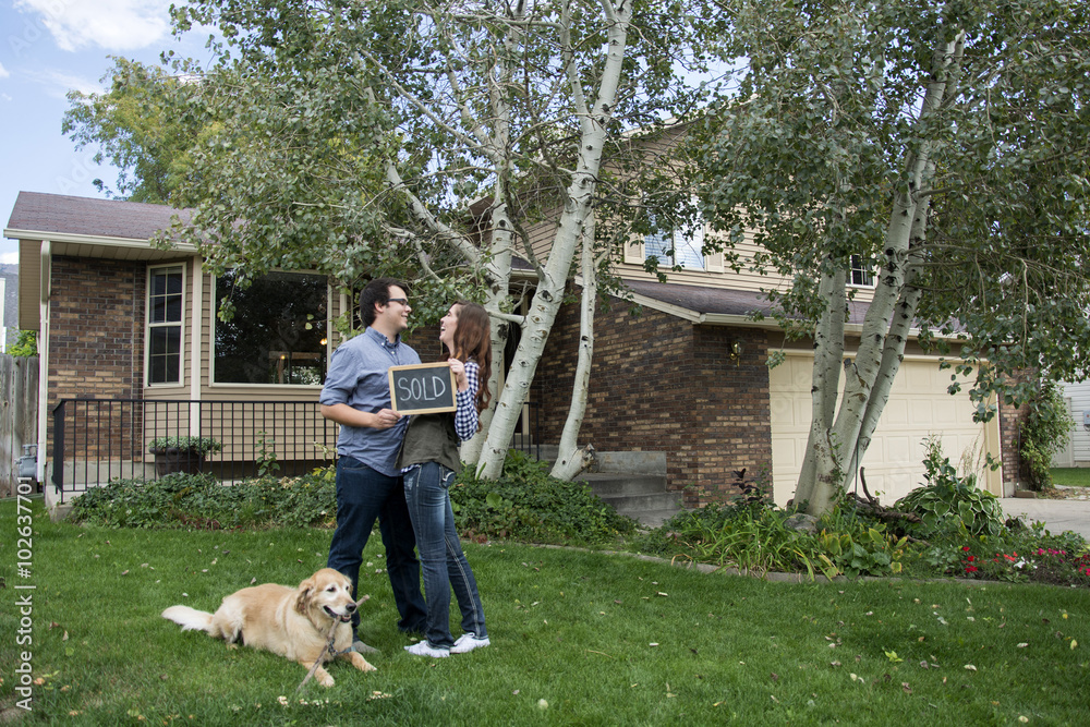 Wall mural couple and dog in front of new home staring at each other with sold sign