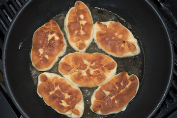 Pasties or pirozhki fried in a pan.