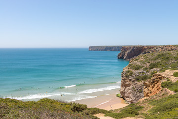 Beliche beach in the Algarve with people surfing.