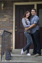 new home owners on front door steps of new home