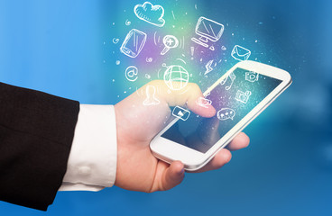 Hand holding smartphone with media icons