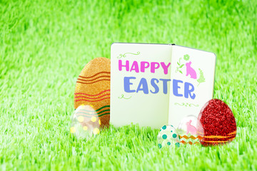 Happy Easter word on Open notebook on green grass with colorful - Powered by Adobe