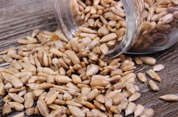 Sunflower seeds spilling out of glass jar. Wooden background