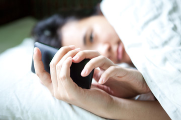 young woman looking smart phone on the bed
