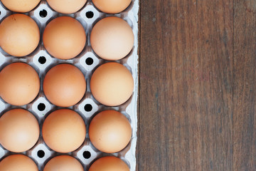 Fresh eggs in egg tray on wooden background