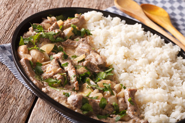 Russian food: beef stroganoff with rice close-up on a plate. horizontal
