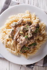 Delicious beef stroganoff with pasta fusilli  close-up. Vertical top view 
