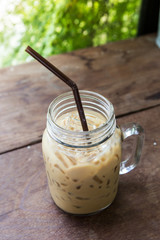 iced coffee in jar on wood table seved in garden blurred backgro