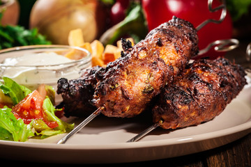 Grilled shish kebab served with fried chips and salad