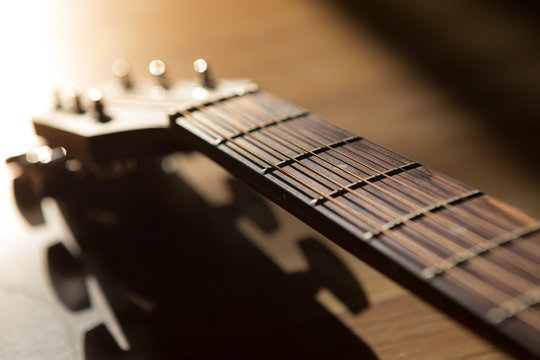 guitar neck with string on blurred wood background light and sha