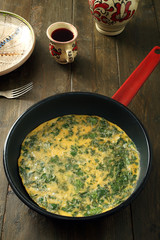 omelette con erbe in padella di metallo sfondo tavolo rustico