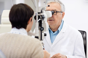 Fototapeta na wymiar Senior eye specialist look in ophthalmoscope and perform eye rev