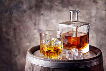 Whiskey with ice on wooden barrel
