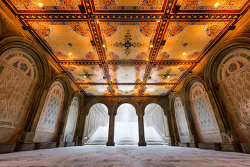 Low angle view of the Bethesda Terrace Arcade during a winter snowstorm with illuminated tile ceiling. Wintertime in Central Park, Manhattan, New York City
