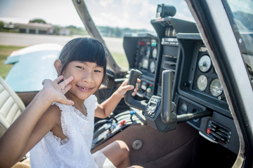 Asian girl in cockpit of plane with sunny day.
