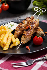 Barbecued kofta - kebeb with fries and vegetables on a plate.
